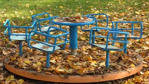 Old carousel that rotates abandoned in a park in autumn, full of leaves Stock Footage 69177749
