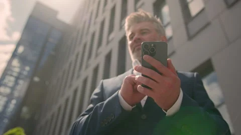 Old Caucasian business man middle aged businessman using mobile phone outdoors Stock Footage 250452853