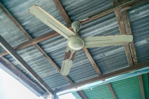 Old ceiling fan is rusted under the roof. Stock Photos