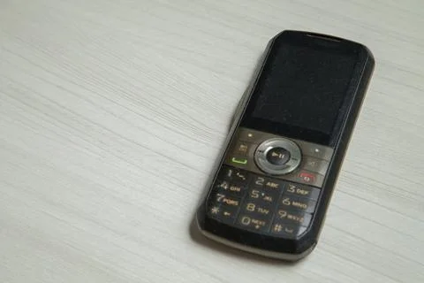Old cellular device placed on the table top in the home office, showing the s Stock Photos