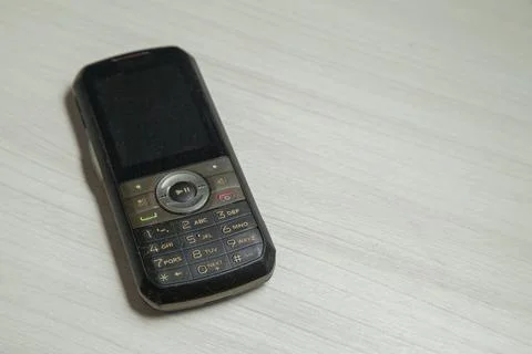 Old cellular device placed on the table top in the home office, showing the s Stock Photos