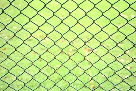 Old chain link pattern abstract fence with green grass field background. Fo.. Stock Photos