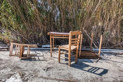 Old chairs and table left on the sand of Santorini beach Stock Photos