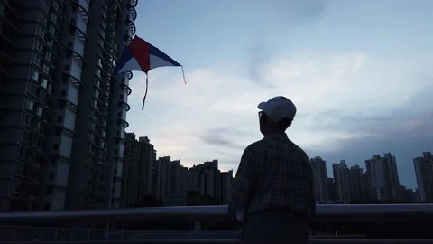 Old Chinese man catching a kite near the river between high buildings, China Stock Footage 159782847