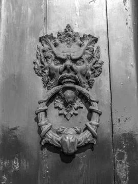 An old clapper on an old door with devil, snikes and a beetle Stock Photos