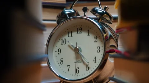 Old classic alarm clock on the background of stacks of books. Stock Footage 245301529