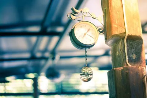 Old clock hanging on a pole in the evening. Stock Photos