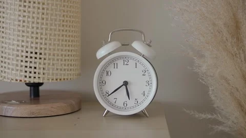 Old clock on a shelf next to a lamp and decorative plant Stock Footage 345188654