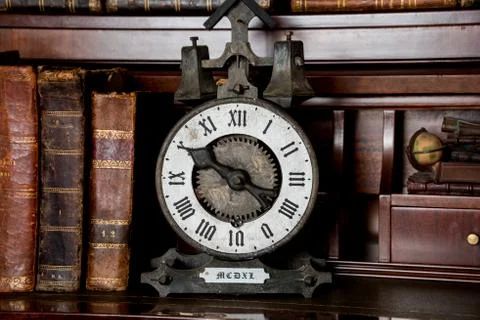 Old clock on shelf with old books Stock Photos