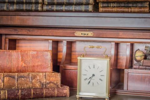 Old clock on shelf with old books Stock Photos