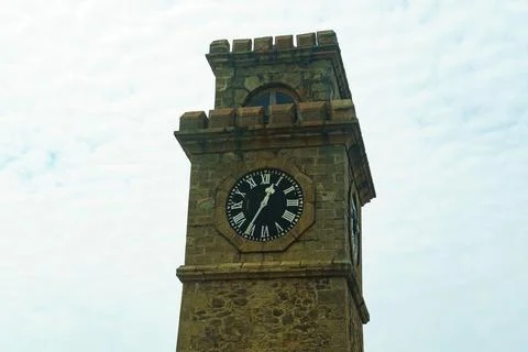 Old clock tower with roman numerals against the sky Stock Photos