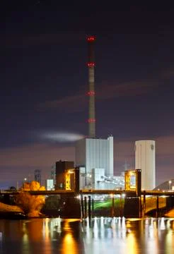 An old coal power station with reflection in the water at night, a bridge in  Stock Photos