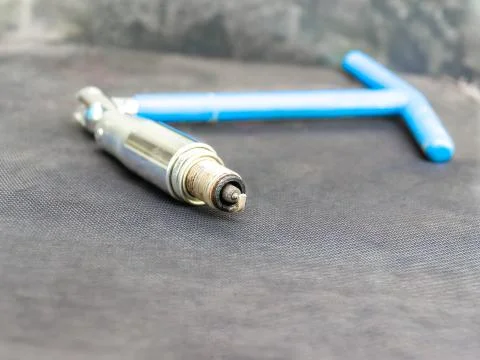 Old coated spark plug in blue hinged key for spark plugs of an internal combu Stock Photos