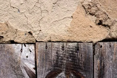 Old cob wall with cracked surface and old wooden boards Stock Photos