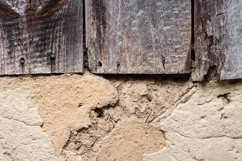 Old cob wall with cracked surface and old wooden boards Stock Photos