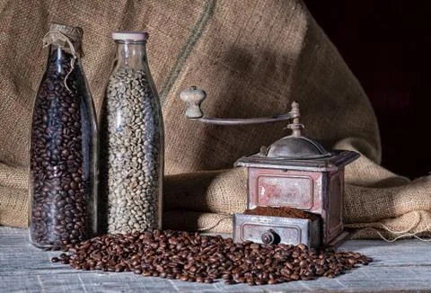 Old coffee grinder and two glass bottles with different coffee beans on mount Stock Photos