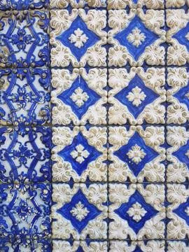 Old colored ceramic tiles. The wall is covered with blue tiles with white pat Stock Photos