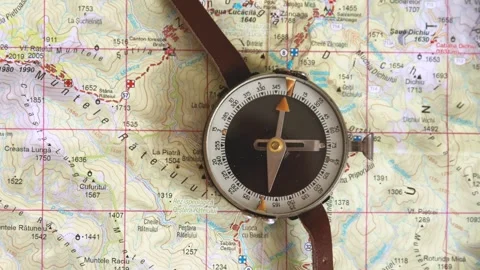 Old compass on map with mountain trails. Compass indicating north on map. Stock Footage 248356113