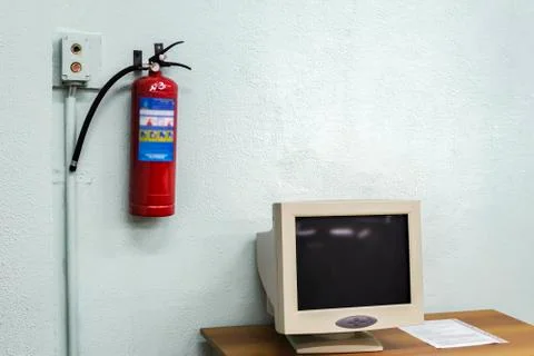 Old computer and a fire extinguisher on the wall Stock Photos