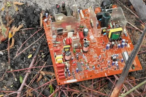 An old computer circuit board is lying in a garbage dump. Stock Photos