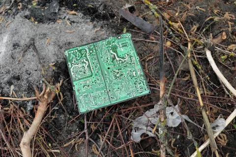 An old computer circuit board is lying in a garbage dump. Stock Photos