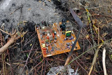 An old computer circuit board is lying in a garbage dump. Stock Photos