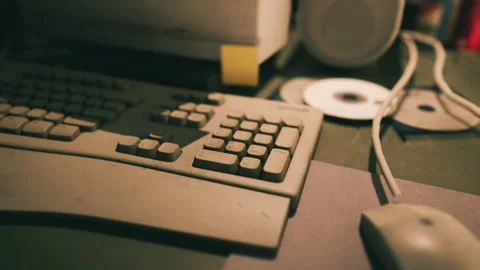 Old computer equipment on a cluttered desk with faded colors in soft lighting 库存影片 293239009