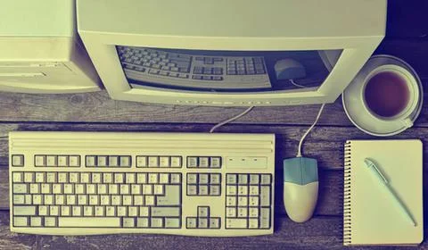 Old computer with keyboard mouse and notepad on wooden desk Stock Photos