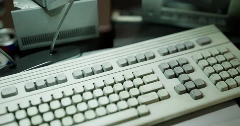 Old computer keyboard resting on a cluttered desk with various items Stock Footage 306304996