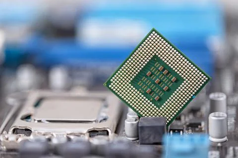 An old computer processor stands on background of motherboard Stock Photos