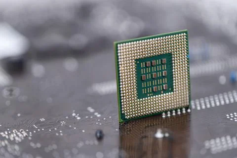 An old computer processor stands on background of motherboard Stock Photos