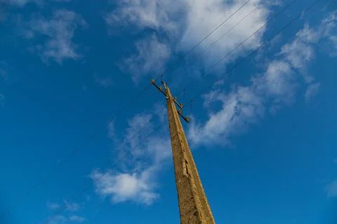Old concrete electric pole with wires and blue sky with some white clouds Foto stock