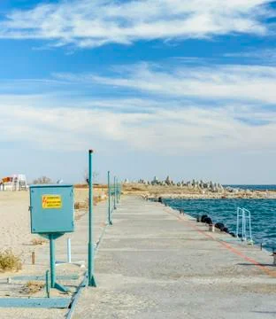Old concrete path in the seaside with a line of rusty transformers Stock Photos