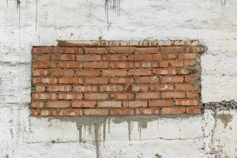 Old concrete wall with a rectangular red brick insert. Cement joints. Stock Photos