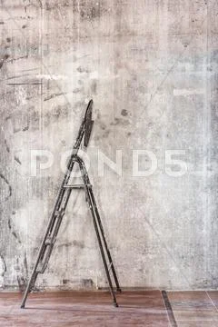 Old concrete wall in repairing room with dirty brown floor and stepladder Stock Photos