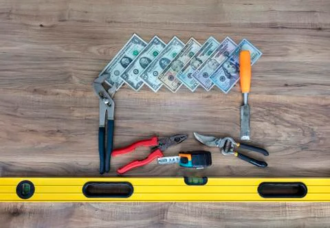Old construction tools and a set of dollar bills on a wooden table close-up Stock Photos