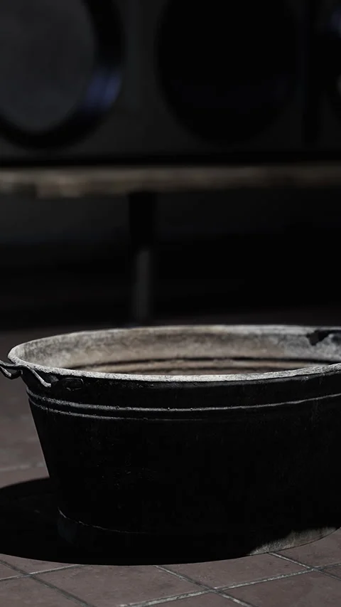 Old cooking pot sits on the kitchen floor in a rustic setting at night Stock Footage 335099092