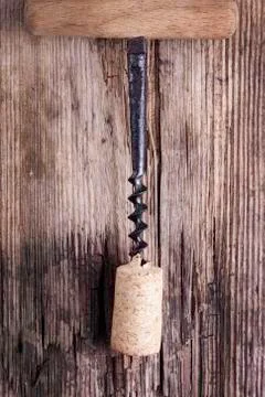 Old corkscrew and wine cork on wooden surface macro closeup Stock Photos
