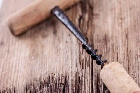 Old corkscrew and wine cork on wooden surface macro closeup Stock Photos
