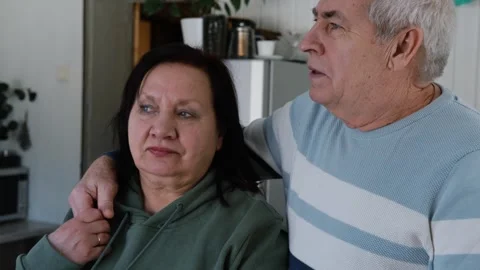 Old couple have breakfast sitting at the kitchen table, drink coffee. Embracing Stock Footage 328621089