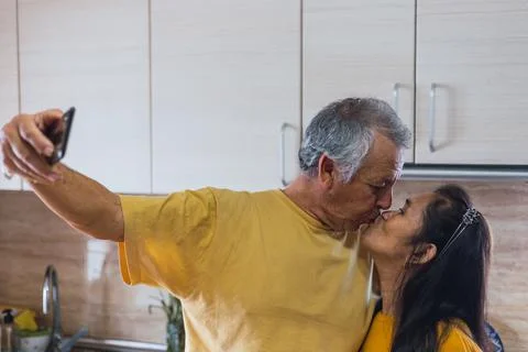 Old couple taking a selfie while kissing. Stock Photos