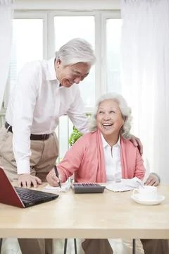An old couple using laptop and calculator Stock Photos