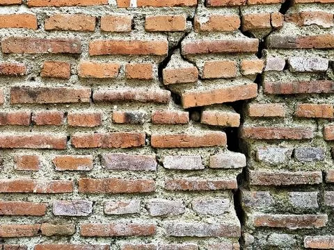 Old Cracked Brick Wall Texture with Deep Fissure and Green Moss Stock Photos