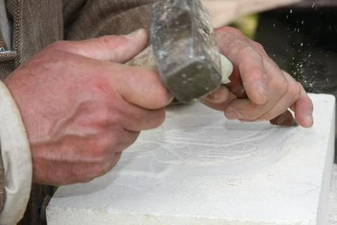 Old craftsman mason during the processing of a piece of white marble 库存照片