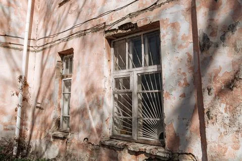 An old, crumbling window with a rusty bars on it. Damaged building Foto stock