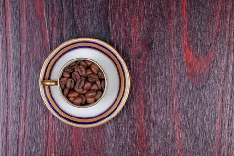 An old cup full of coffee beans with its plate Foto stock