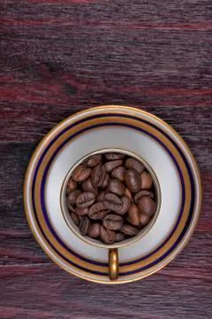 An old cup full of coffee beans with its plate Stock Photos