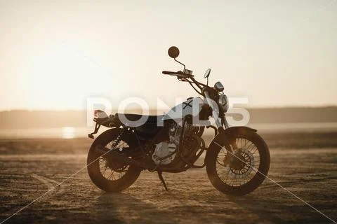 old custom beautiful cafe racer motorcycle in the desert at sunset or sunrise Stock Photos