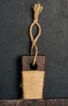 An old cutting board handle made of dark wood, wrapped in natural jute twin.. Photos