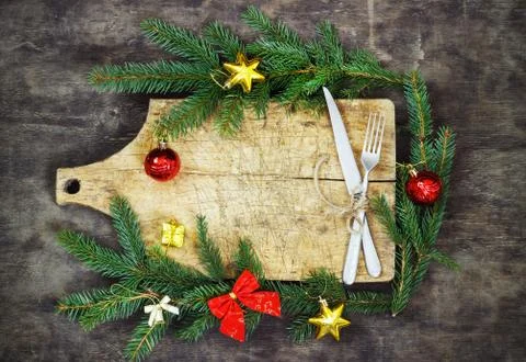 Old cutting board with spruce branches on a wooden background with fork and k Stock Photos